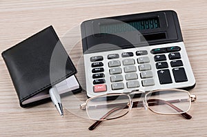 Calculator, notepad, pen and glasses on table