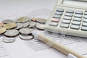 Calculator, pen and coins on savings account passbook or financial statement
