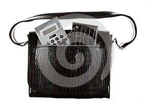 Calculator, pen and passport sticks out of a leather bag pocket. On a white background