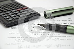 Calculator and pen on scientific paper
