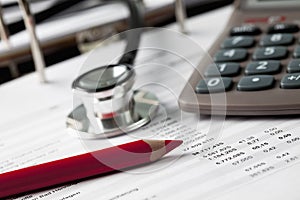 Calculator with pen and stethoscope and form, close up