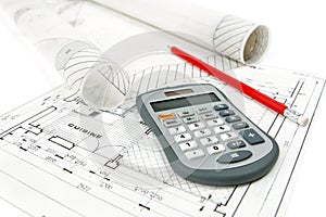 Calculator and pencil on house plan with rolls of architectural drawings