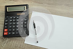 Calculator and pencil and white paper on a wooden desk. Calculation concept selective focus