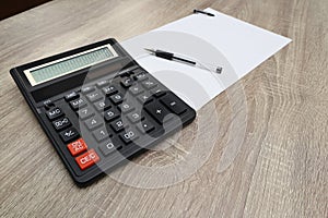 Calculator and pencil and white paper on a wooden desk. Calculation concept selective focus