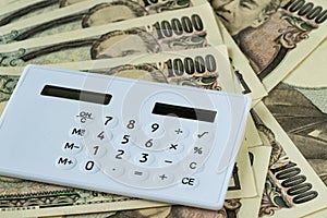 Calculator on pile of japanese yen banknotes as financial safe h