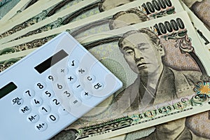 Calculator on pile of japanese yen banknotes as financial safe h