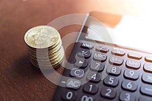 Calculator and a stack of Bitcoins coins as symbol of cryptocurrency digital money in the future blockchain