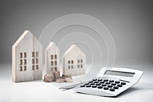 Calculator with wooden house and stack of coins