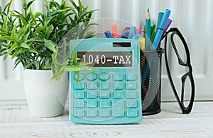 calculator with the word 1040-TAX on the display with chart and glasses