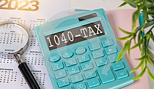 Calculator with the word 1040-Tax on display and magnifying glass