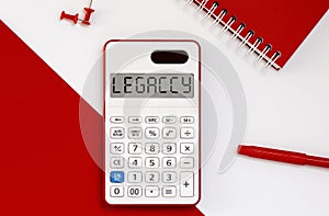 Calculator with the word LEGACY on the display with red notepad and office tools