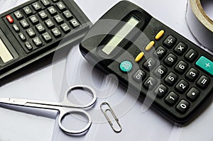 Calculators, scotch, scissors and a clip on a white background