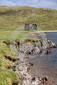 Ruins of Calda House set against verdant Scottish Highlands, with rugged shoreline leading the view photo