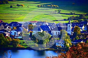 caldera lake Schalkenmehrener Maar with the village Schalkenmehren in autumn