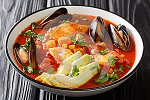 Caldo De Mariscos Recipe seafood soup with cod, shrimp, mussels, vegetables and avocado close-up in a bowl. Horizontal