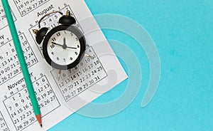 Calendar with alarm clock on blue background. Time management concept