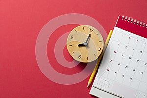 Calendar and alarm clock on the red table background, planning for business meeting or travel planning concept