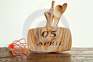 Calendar for April 5: on a kitchen wooden board the name of the month April in English, the numbers 05, next to various kitchen