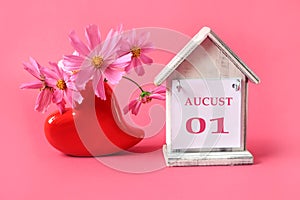 Calendar for August 1 : the name of the month of August in English with the numbers 0 and 1 on a toy house, a bouquet of pink