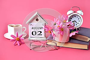 Calendar for August 2 : the name of the month of August in English, the numbers 0 2, a cup of tea, books, a bouquet of pink