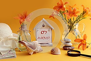 Calendar for August 7: decorative house with numbers 07, name of the month august in English, bouquets of daylilies, sea shells