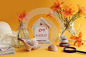 Calendar for August 9: decorative house with numbers 09, name of the month august in English, bouquets of daylilies, sea shells