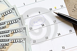 Calendar with blue marker circle in word payday and American dollars cash money for remind photo