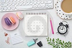 Calendar with clock, coffee cup and candy on office table