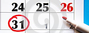 Calendar in close-up on a blue background. Red marker on the calendar. The 31th number in the calendar is circled in red with a