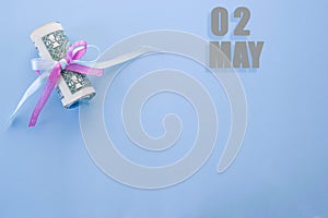 Calendar date on blue background with rolled up dollar bills pinned by blue and pink ribbon with copy space.  May 2 is the second