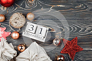 Calendar with date of December 31. Around New Year and Christmas decorations, gifts wrapped in cloth. Copy space on wood