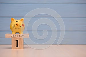Calendar date of Financial Year start, 1st january with piggy bank on blue background. Winter time.