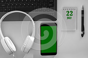 calendar date on a light background of a desktop and a phone with a green screen. July 22 is the twenty-second day of the month