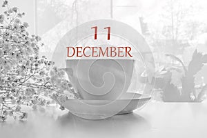 Calendar date on light background with porcelain white tea pair and white gypsophila with copy space. December 11 is the eleventh