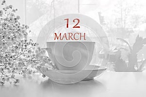 Calendar date on light background with porcelain white tea pair and white gypsophila with copy space. March 12 is the twelfth day