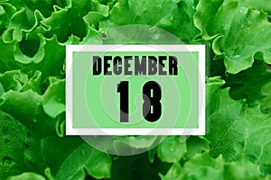 Calendar date oncalendar date on the background of green lettuce leaves. December 18 is the eighteenth day of the month