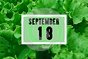 Calendar date oncalendar date on the background of green lettuce leaves. September 18 is the eighteenth day of the month