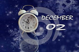 Calendar for December 2: white alarm clock on a blue background with bokeh, reflection from objects, name of the month december,