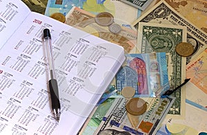 Calendar on euro and dollar bills, calculator, ink pen and coin money background.