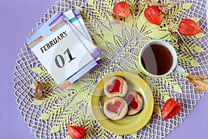 Calendar for February 1: the name of the month February in English, the numbers 01 on the loose-leaf calendar, a cup of tea, heart