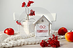 Calendar for February 2: the name of the month February in English, the numbers 02 on a decorative house among the branches of