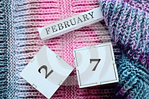 Calendar for February 27: cubes with the numbers 27, the name of the month of February in English on multi-colored jersey, top photo