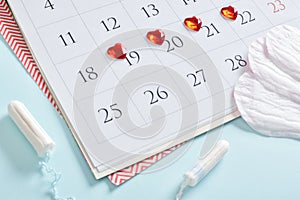 Calendar of the female menstrual cycle with pads and tampons on a light blue background.