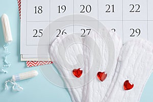 Calendar of the female menstrual cycle with pads and tampons on a light blue background.