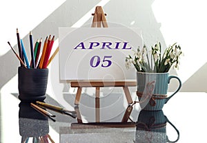 Calendar for the fifth of April: an easel with the inscription April in English and the numbers 05, a bouquet of snowdrops in a
