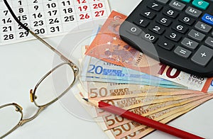 Calendar, glasses, red pencil, euros and calculator