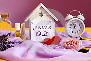 Calendar for January 2: decorative house with the name of the month in English, number 02, various cosmetics, white alarm clock,