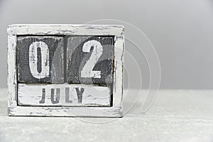 Calendar for July 02, made of wooden cubes, on gray background.With an empty space for your text.