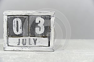 Calendar for July 03, made of wooden cubes, on gray background.With an empty space for your text.