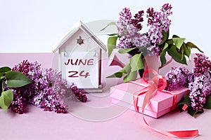 Calendar for June 24: a decorative house with the name of the month of June in English, the number 24, bouquets and lilac